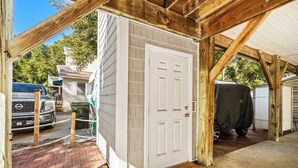 A garage with a white door, wooden beams, and a covered vehicle.