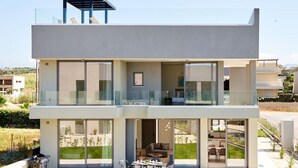 Ein modernes, zweistöckiges Haus mit Balkon, großen Fenstern und einem gepflegten Rasen.