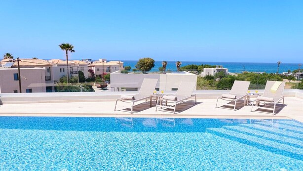 Ein Pool mit Liegestühlen und Meerblick.