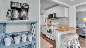 A kitchen with white cabinets, a microwave, a coffee maker, and a wooden countertop. - Heated Salt Water Pool & Fire Pit Retreat in Sarasota (Sarasota)