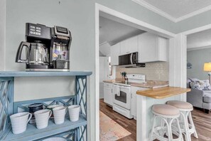 A kitchen with white cabinets, a microwave, a coffee maker, and a wooden countertop.
