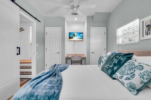 A bedroom with a bed, a desk, and a ceiling fan.