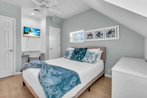 A bedroom with a bed, a desk, and a chair.