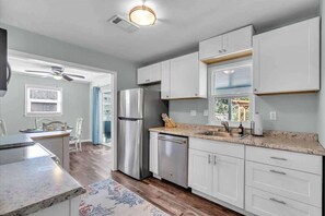 A modern kitchen with white cabinets, stainless steel appliances, and a granite countertop.