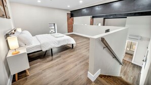 Une chambre d’hôtel moderne, équipée d’un lit, d’une table de chevet et d’un petit bureau.
