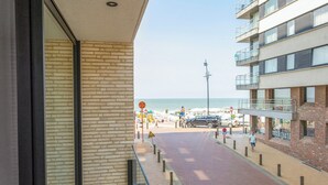 A balcony with a view of a beach and a multi-story building. - Apartment in Blankenberge Near the Beach (Blankenberge)