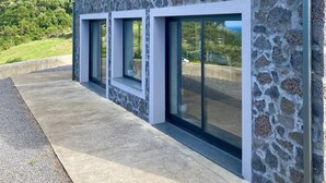 Un edificio moderno con fachada de piedra, amplias ventanas y vista a un paisaje verde.