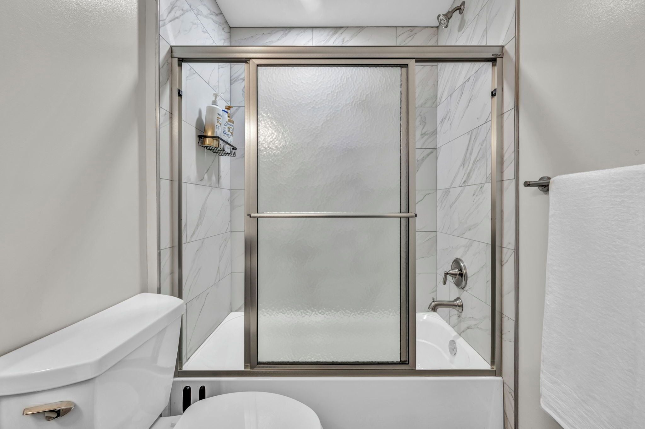 Une salle de bain moderne avec une douche à parois de verre, des toilettes blanches et une baignoire.