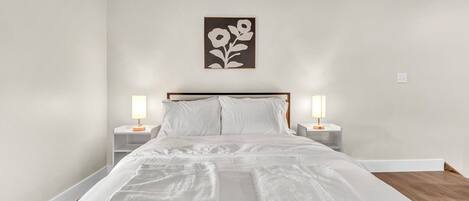 A neatly made bed with white linens and two bedside lamps.