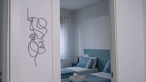 A bedroom with two beds, a headboard, and a wall art of a face.
