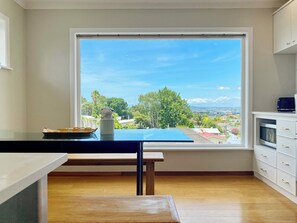 Enjoy a panoramic view of the surrounding area from this kitchen's large window, featuring an oven and a wooden table.