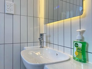 Bathroom features a white sink, mirror, and tiled walls.