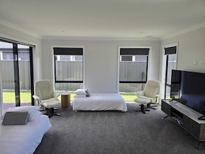Une chambre d’hôtel moderne avec un grand lit, deux fauteuils, une télévision et de grandes fenêtres.