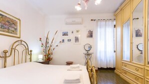Una habitación de hotel con cama, tocador con espejo, mesita de noche con lámpara y una pared decorada con cuadros.