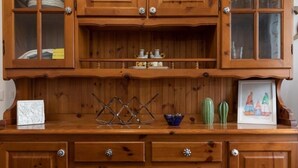 Un mueble de madera con puertas de cristal, cajones y un adorno metálico en la parte superior.