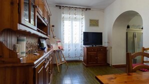 Una cocina con armarios de madera, una mesa de comedor, un televisor y un refrigerador.