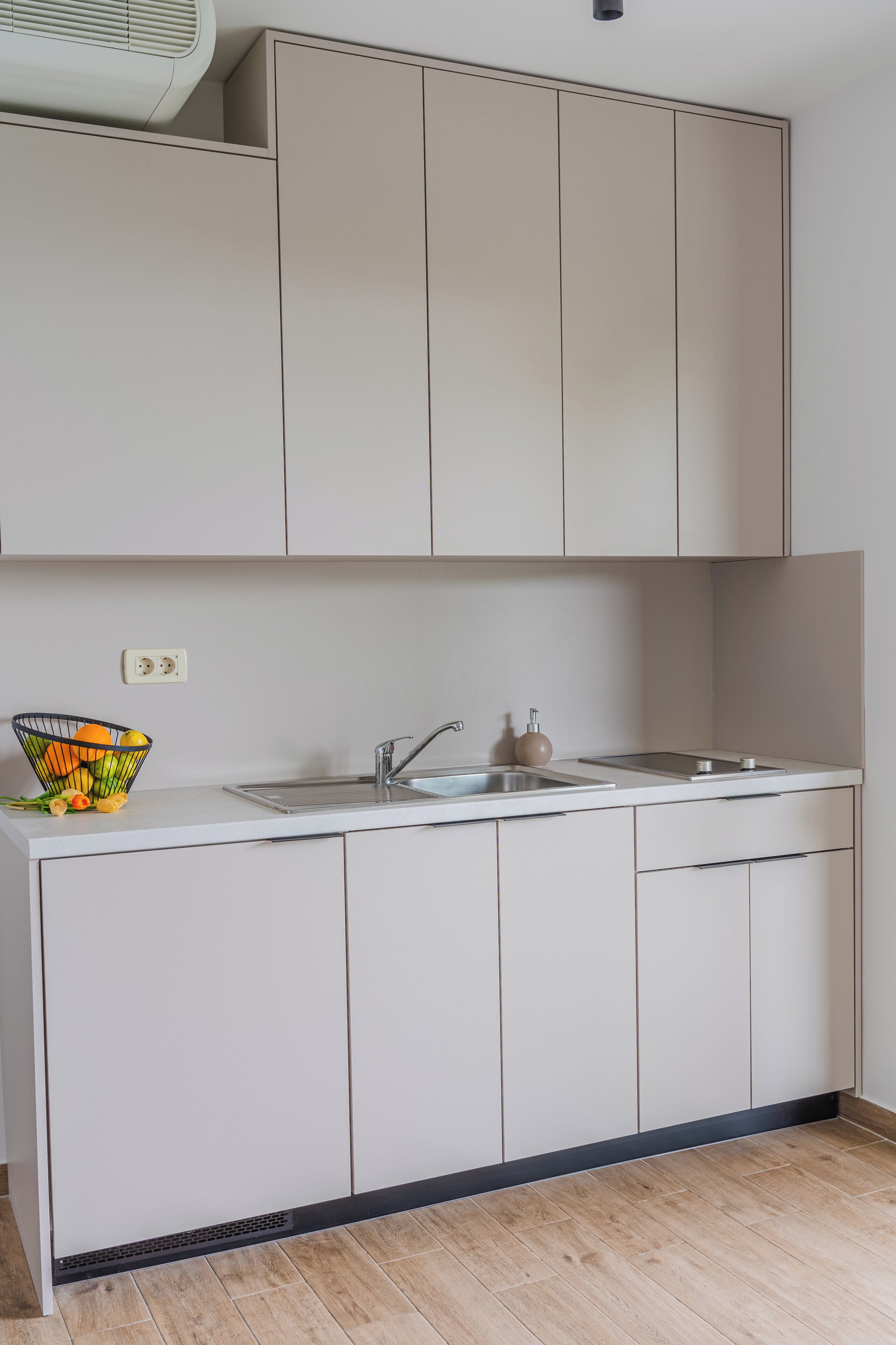 A modern kitchen with white cabinets, a stainless steel sink, and a fruit bowl on the countertop.