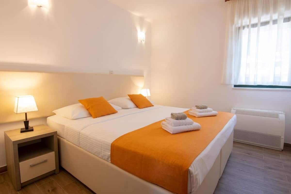 A hotel room with a bed, nightstand, and a window with curtains.