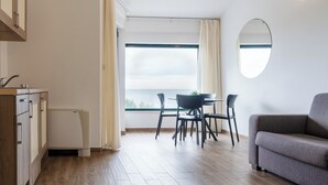 Eine moderne Küche mit Essbereich, einer Couch und Blick aufs Meer.