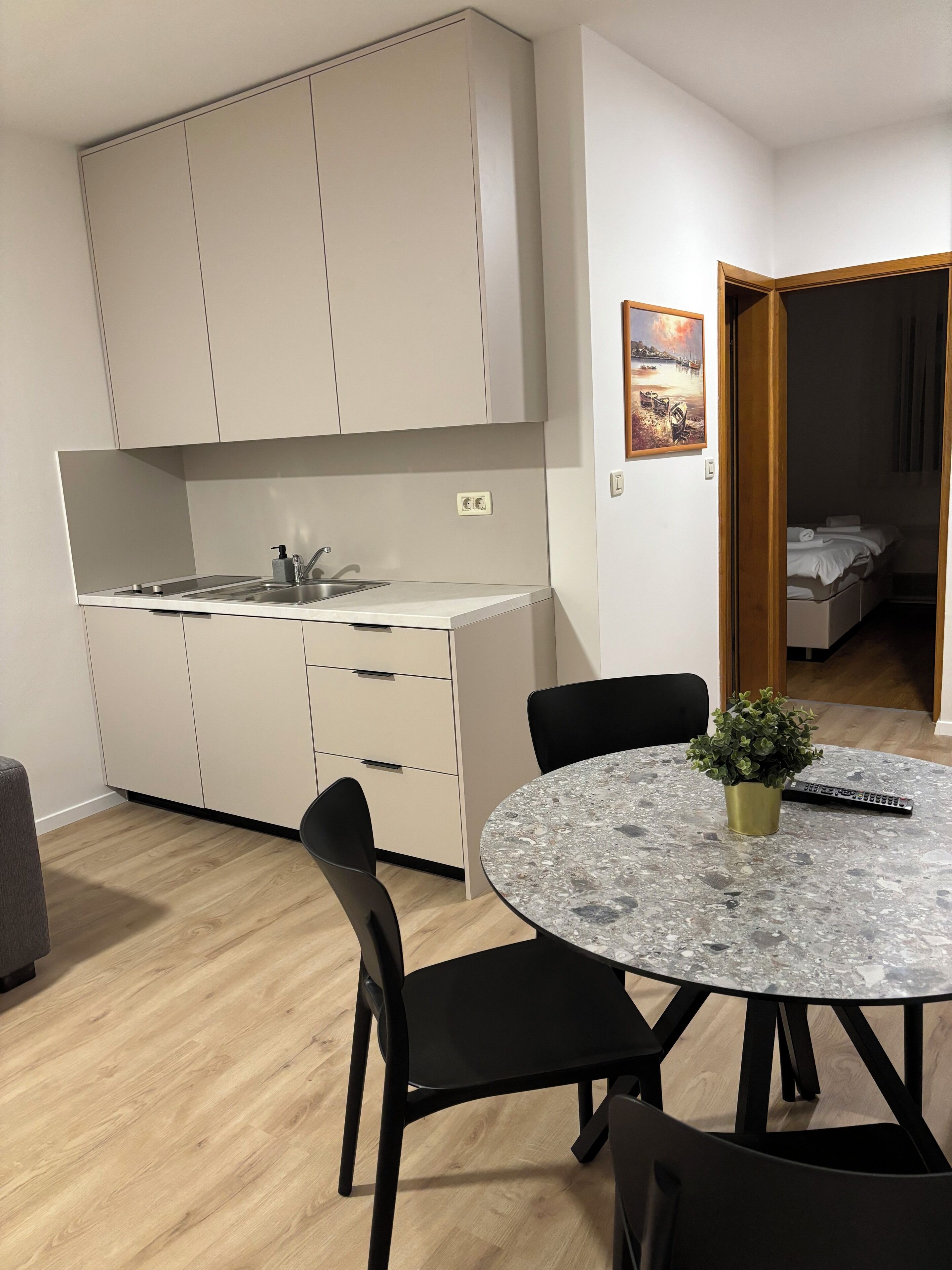 Une cuisine de taille réduite comprenant un évier, des placards et un coin repas avec une table et des chaises.