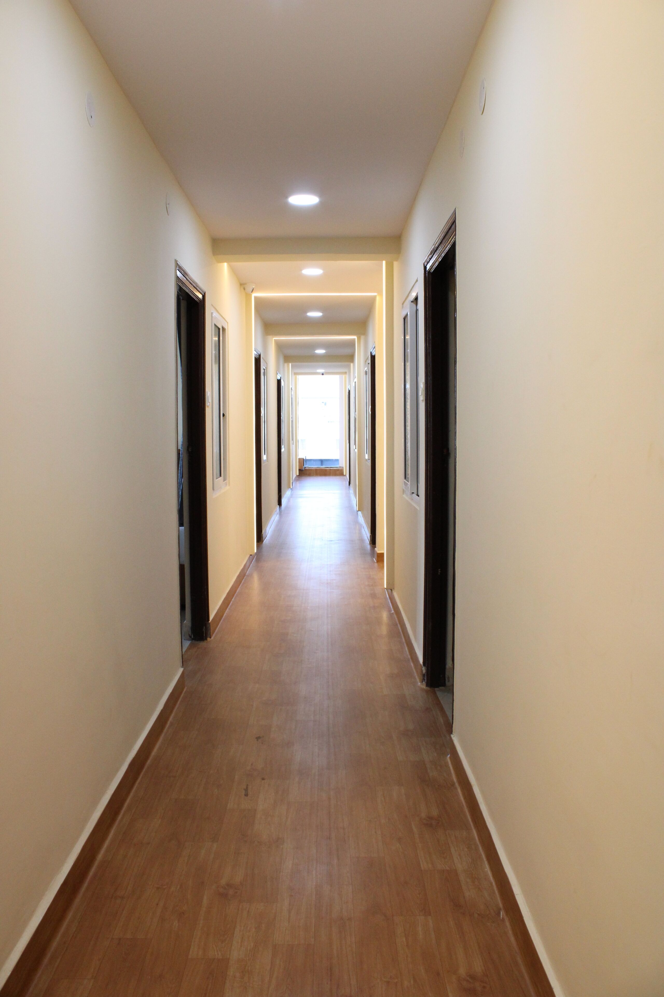 A long, narrow hallway with wooden flooring and cream-colored walls.