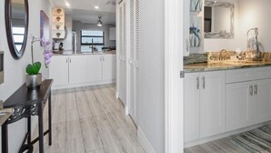 Una cocina moderna con armarios blancos, encimera de mármol y un espejo grande sobre el lavabo.