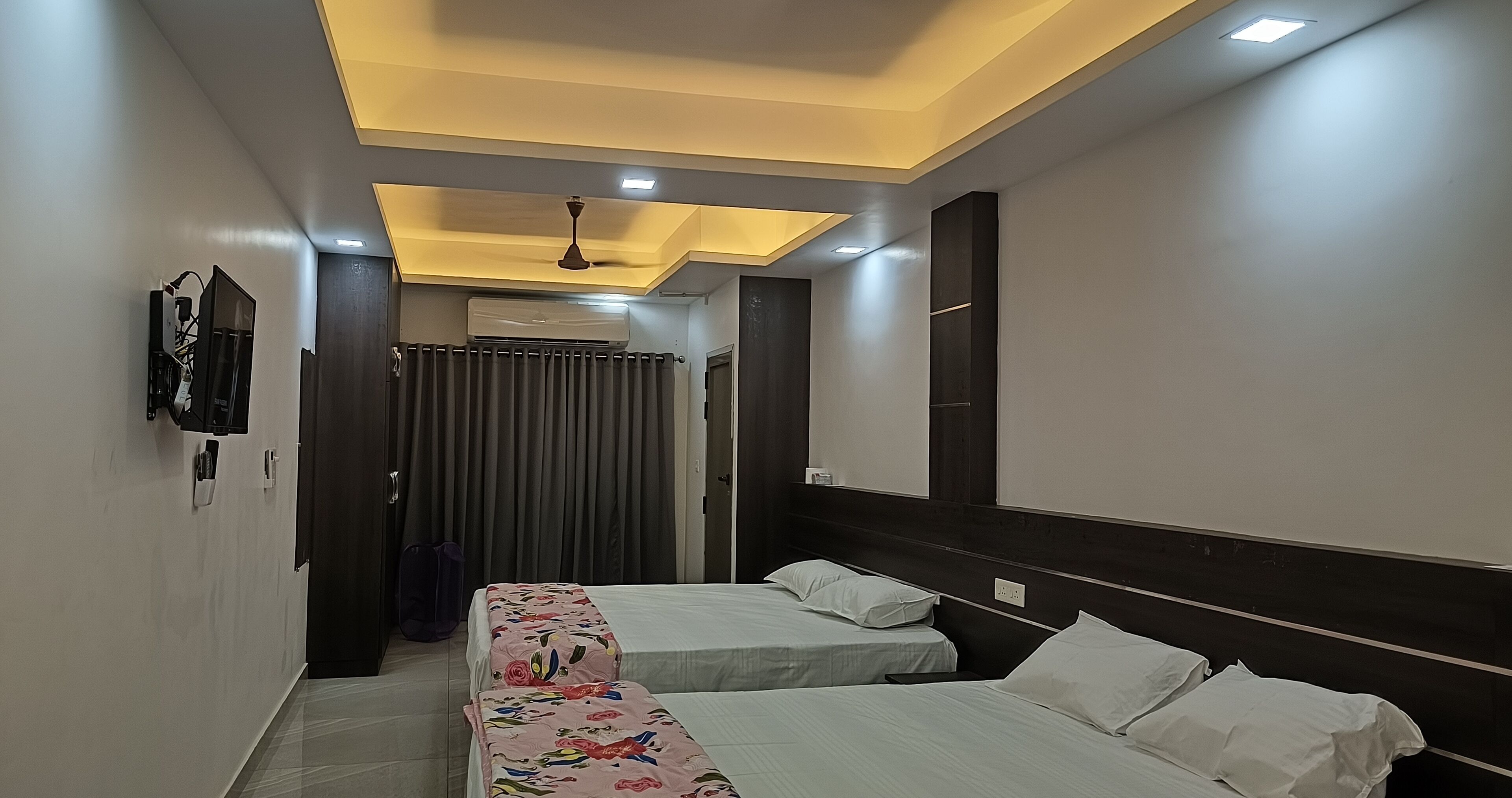 Ein Hotelzimmer mit zwei Betten, einem Deckenventilator, einer Klimaanlage und einem Spiegel an der Wand.