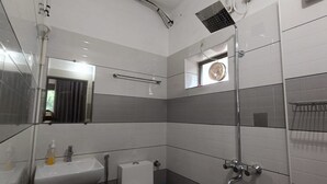 Een moderne badkamer met een grote spiegel, een douche en een klein raam.