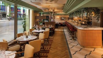 A restaurant with round tables, chairs, and a bar area.