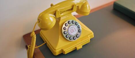 A yellow rotary dial telephone on a wooden table.