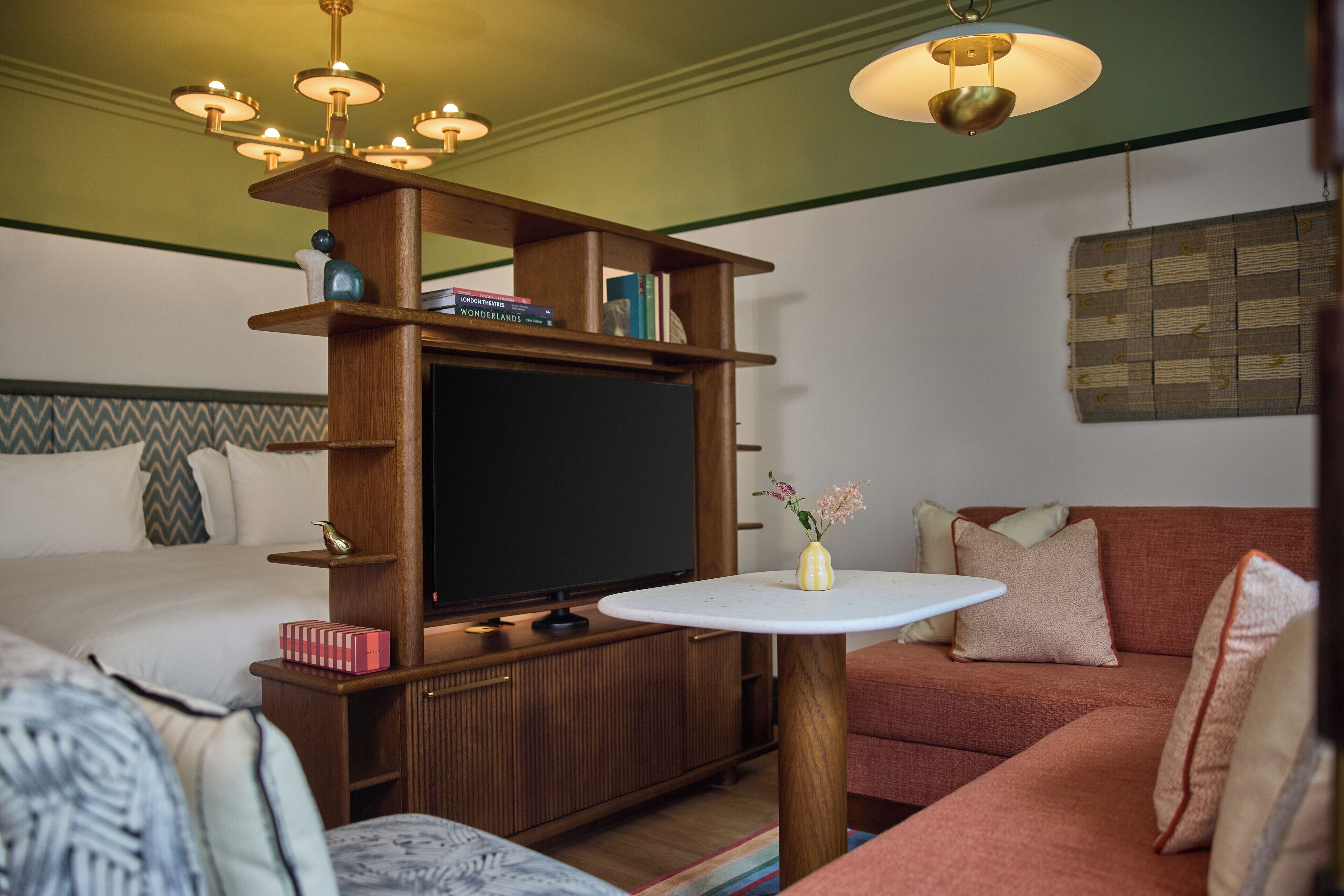 Ein gemütliches Zimmer mit einem Bett, einem Sofa, einem Fernseher und einem kleinen Tisch mit einer Vase.