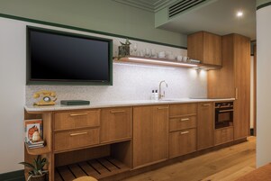 Una cucina con mobili in legno, un piano di lavoro, un forno integrato e una televisione a parete.