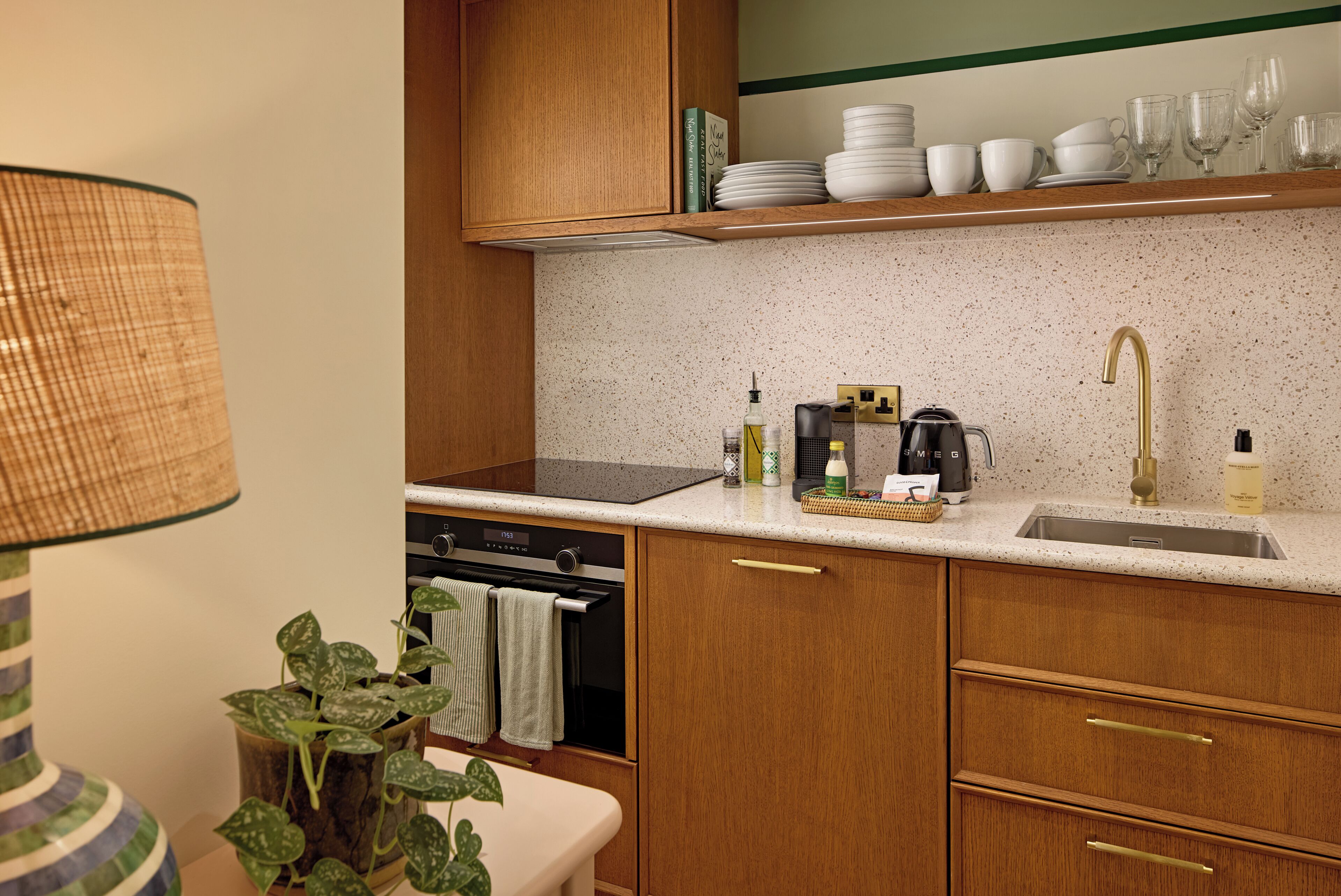 A kitchen with wooden cabinets, a countertop, a sink, a stove, and a coffee maker.