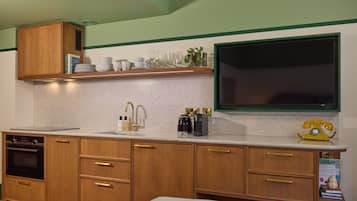 Une cuisine avec des meubles de rangement en bois, un plan de travail, un évier, une cuisinière et un téléphone à cadran jaune.