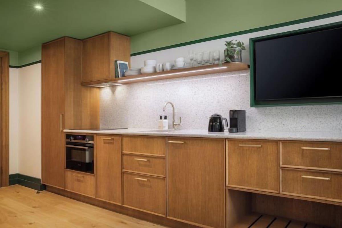 A modern kitchen with wooden cabinets, a countertop, a sink, and a black coffee maker.
