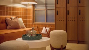 A cozy room with a sofa, a table with a lamp, and a window with blinds. - The July London Victoria (London)