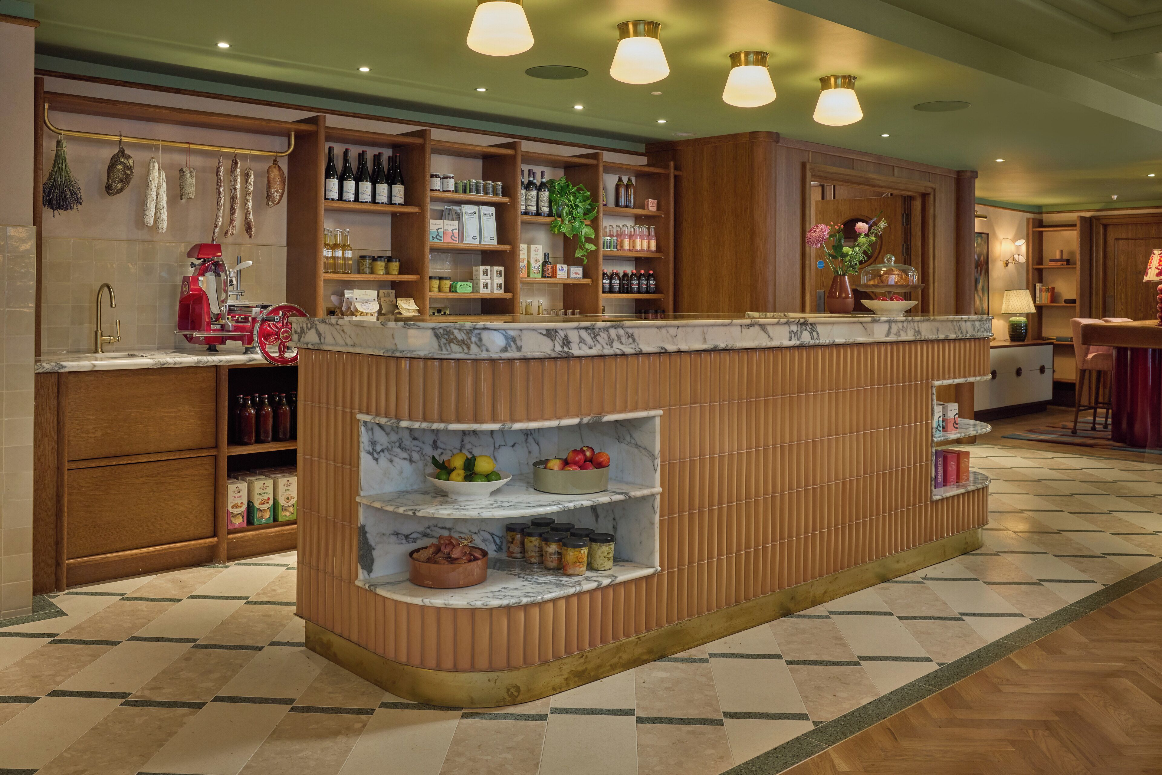 A hotel lobby with a marble reception desk, wooden shelving with various items, and a tiled floor.