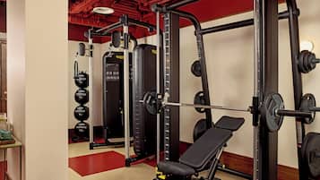 A gym with weightlifting equipment, a bench, and a mirror.