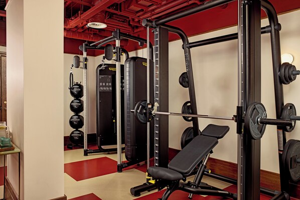 Une salle de sport équipée de matériel de musculation, d’un banc et d’un miroir.