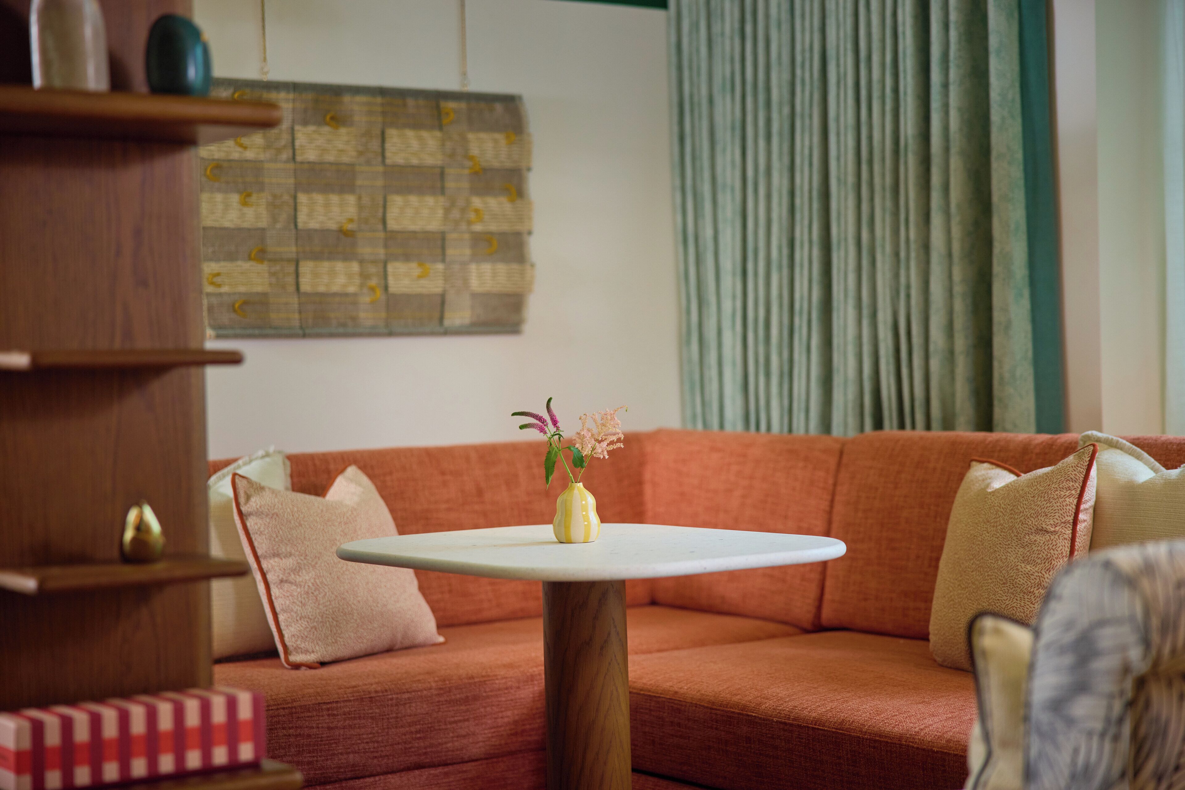 Ein gemütliches Wohnzimmer mit einem Holztisch, einem roten Sofa und einer dekorativen Vase mit Blumen.