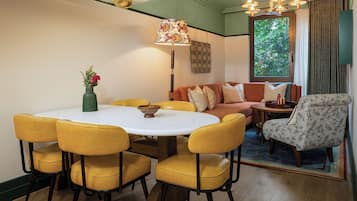 A dining area with a round table, yellow chairs, and a vase of flowers.