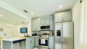 A modern kitchen with grey cabinets, a stainless steel refrigerator, a microwave, and a dishwasher. - Modern 2-bedroom Retreat Near Beach Airport (Fort Lauderdale)