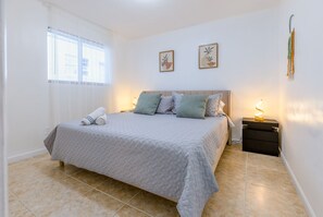 Ein Schlafzimmer mit Bett, Nachttischen und einem Fenster mit Jalousien.