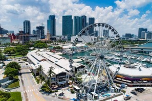 A Ferris wheel surrounded by a marina with boats, a modern city skyline, and a building labeled "SPORTIVE". - Tropical House Pool Table Jacuzzi Nearby Beach (Pompano Beach)