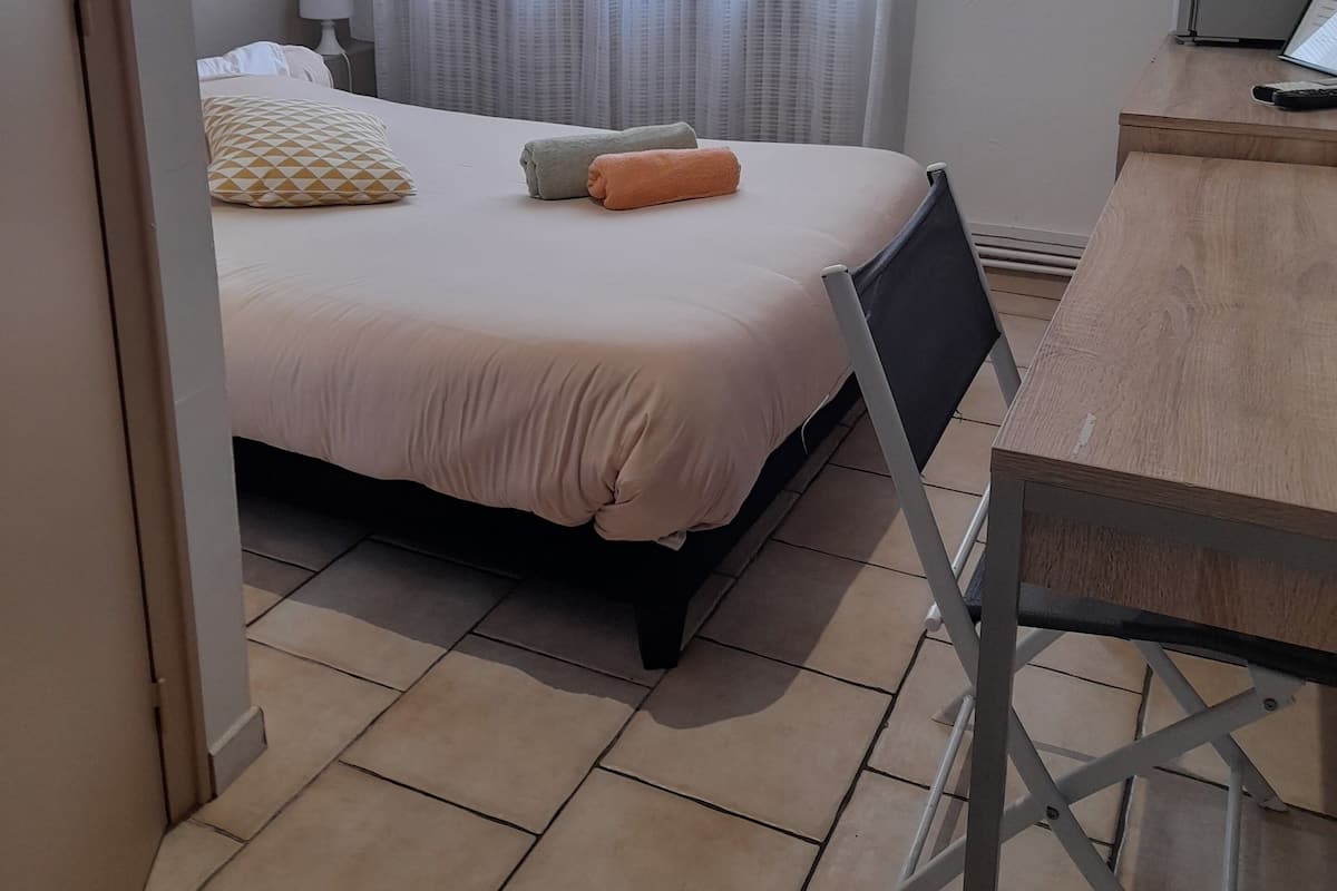 A bedroom with a bed, a desk, and a chair.