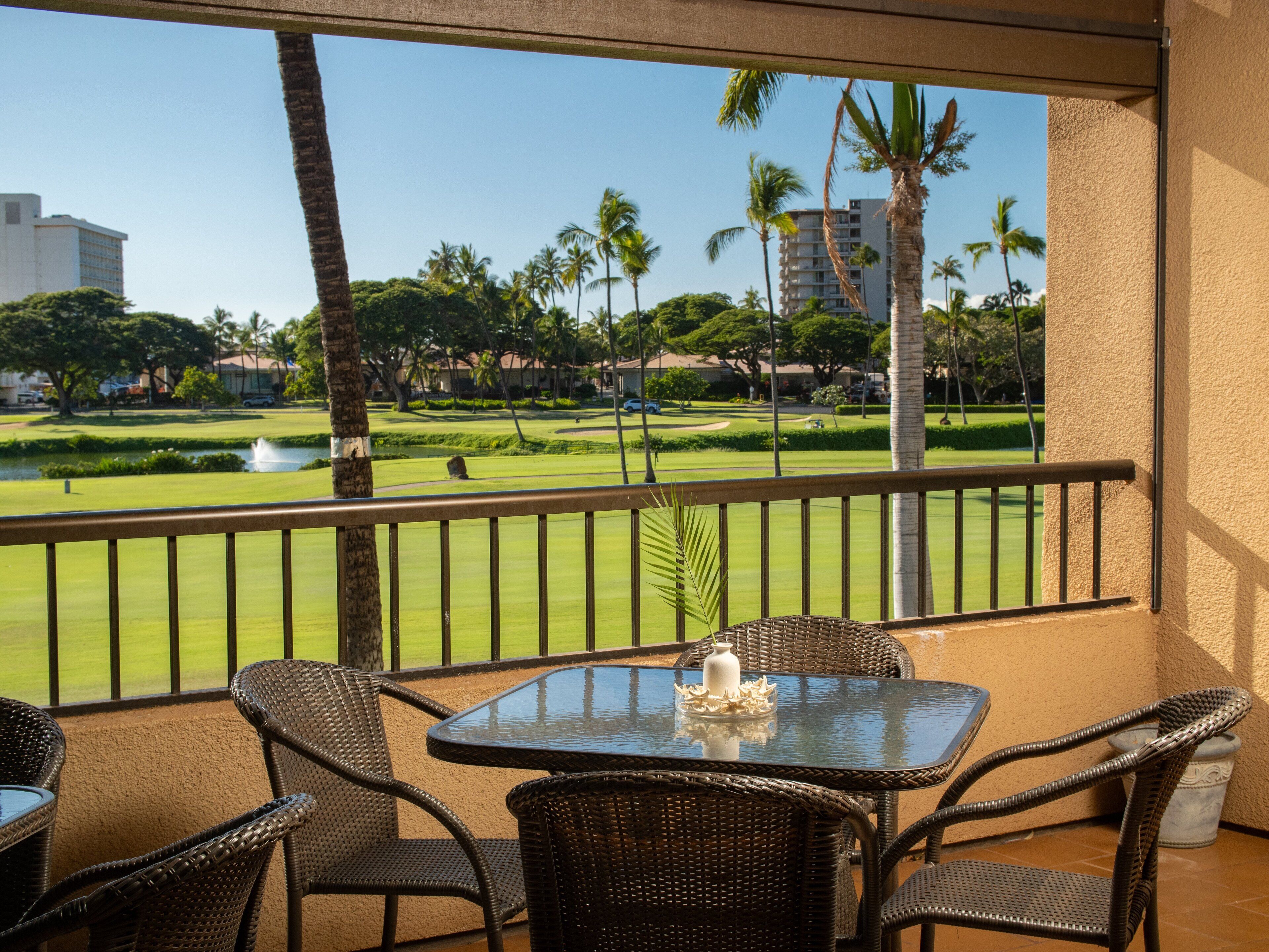 A balcony with wicker furniture and a view of a golf course.