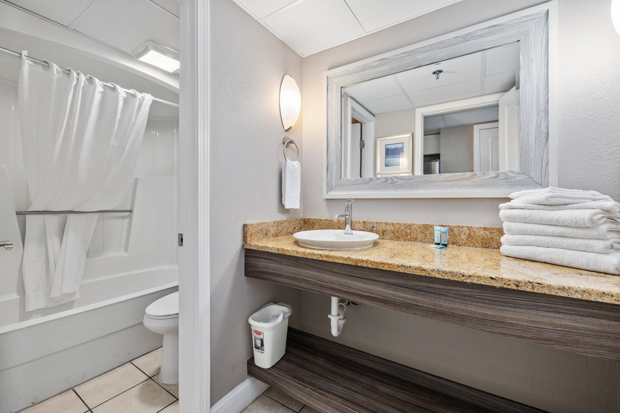 Une salle de bain avec un lavabo, un miroir et un rideau de douche.