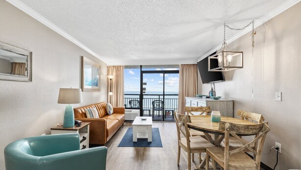 Una camera d'albergo moderna con zona living, angolo ristoro e balcone con vista.