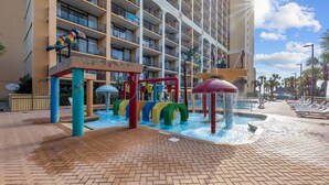 Un hotel con area giochi d'acqua, comprensiva di uno scivolo colorato e di una fontana.