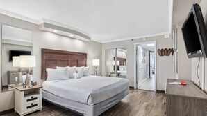 Una camera d'albergo moderna con un ampio letto, comodini, una TV a schermo piatto e uno specchio.